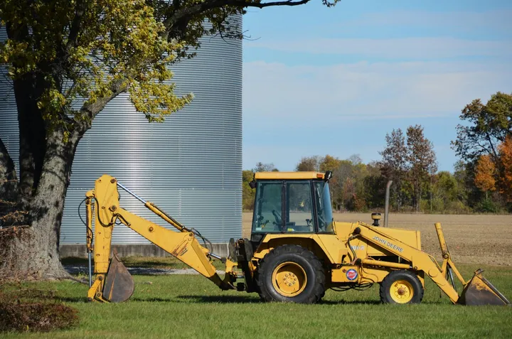 Backhoe loader parked beside a silo